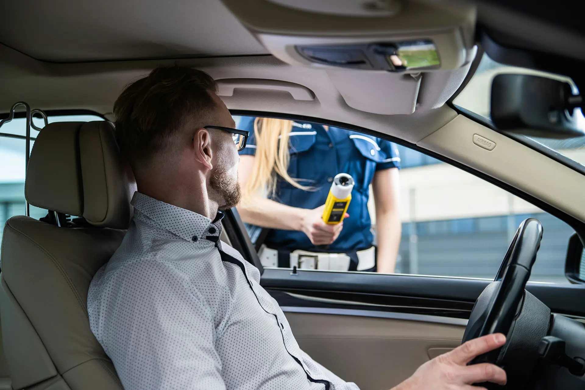 Kontrola drogowa kierowcy przez policję, test trzeźwości wykonywany alkomatem; zdjęcie ilustrujące sytuację prawną, w której pomoc doświadczonego adwokata i przygotowanie linii obrony mogą uchronić przed dożywotnim zakazem prowadzenia pojazdów.